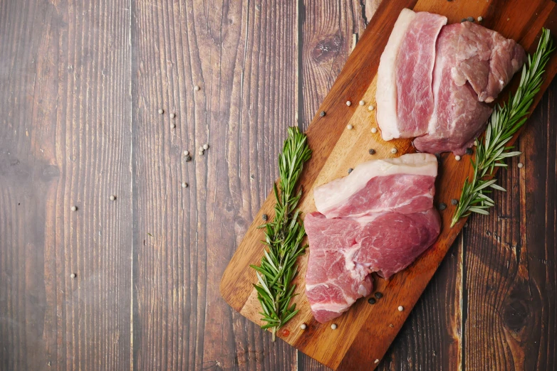 two cuts of meat on  board with rosemary sprigs