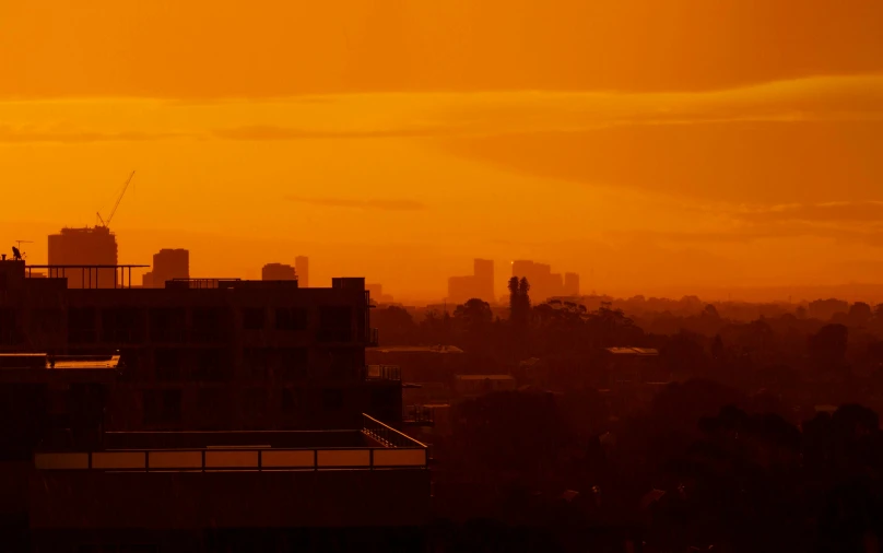 city skyline seen across large orange sky at sunrise