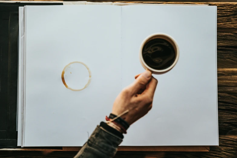 an open book in the hands of someone who is holding a coffee mug