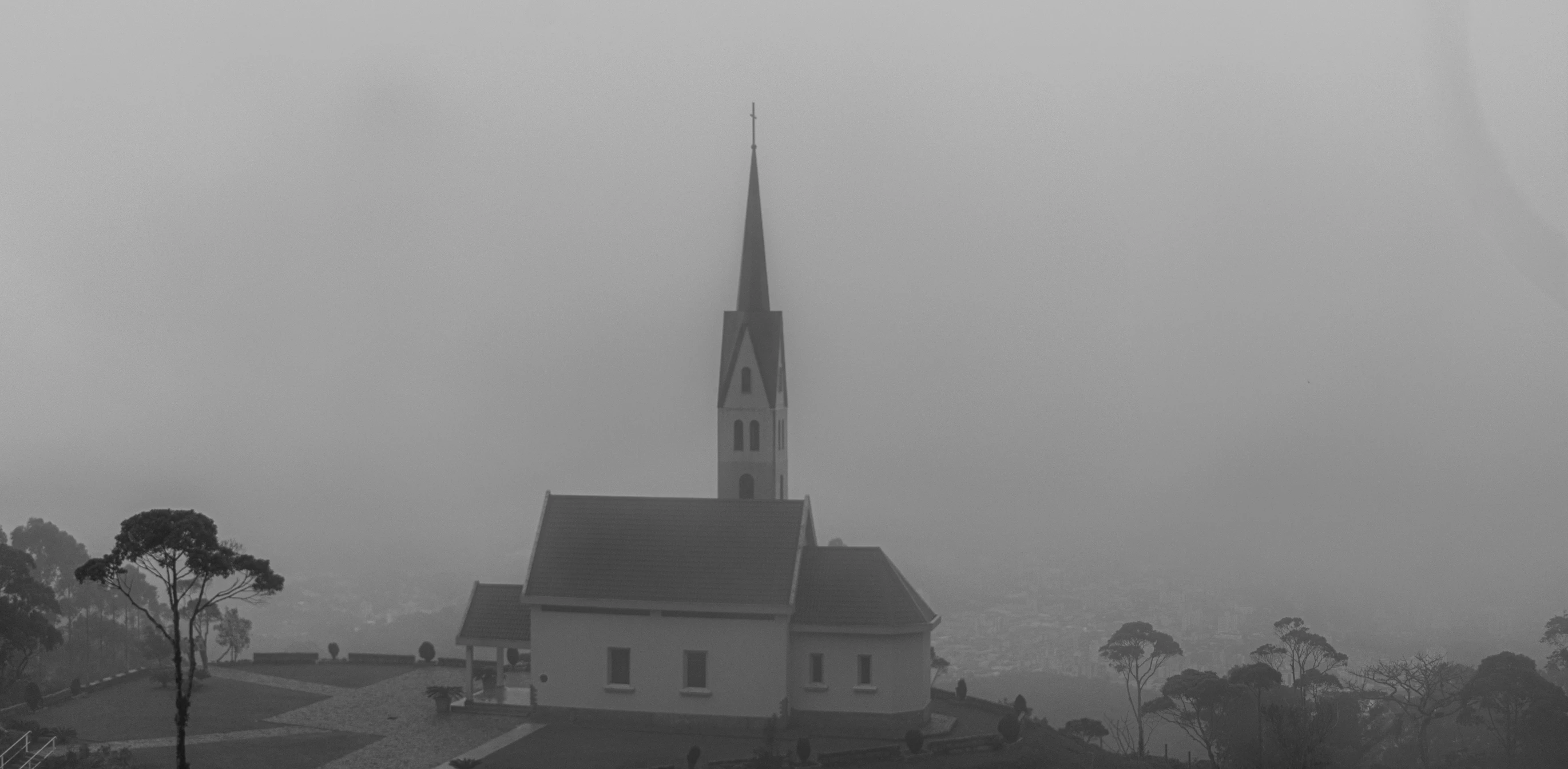 a steeple on the side of a church near many trees