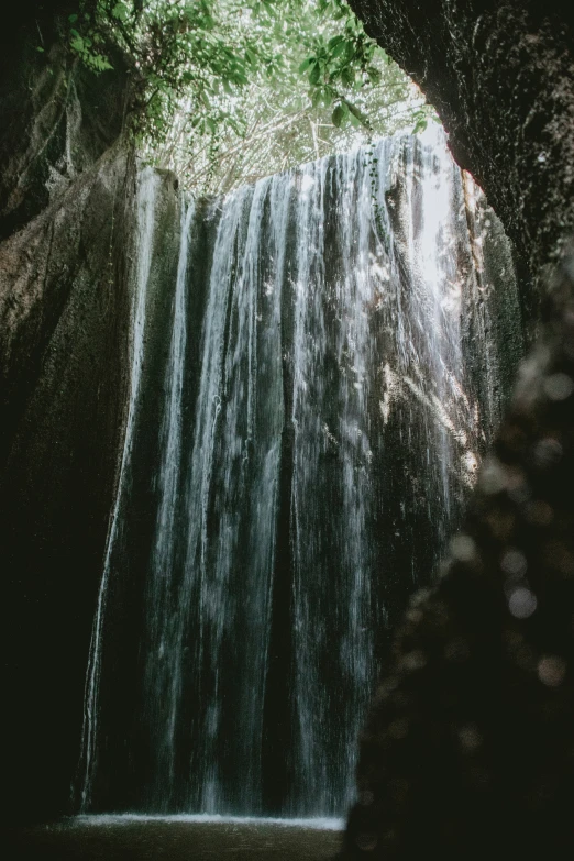 water fall coming from under a lush green forest