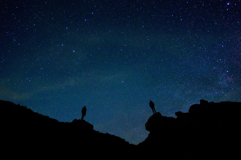 two people stand on top of a cliff