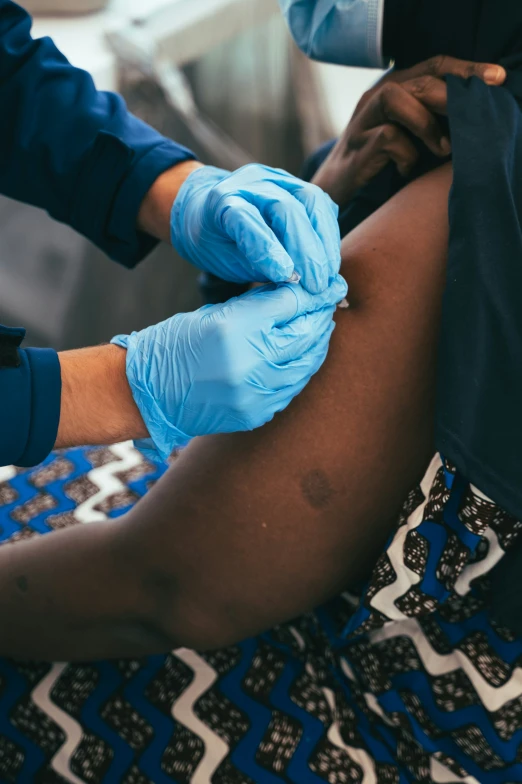 a person in latex gloves and blue gloves on another person