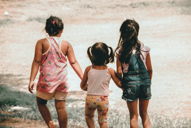 two girls and an infant are standing in front of some water