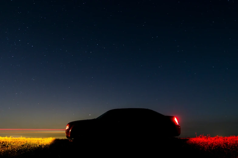 a vehicle with headlights lit up sitting next to the grass