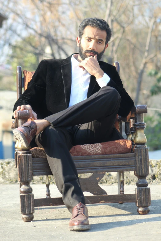 a man sitting in a chair outside and staring off into the distance