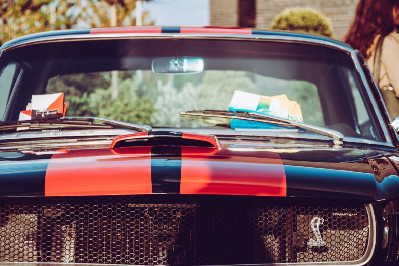 a close - up of a vintage mustang with an orange black and blue stripe on the front