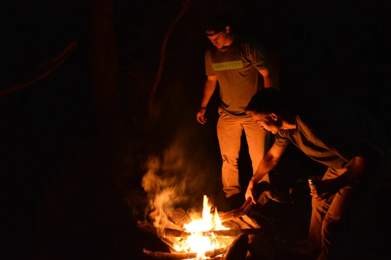 people are standing around a campfire at night