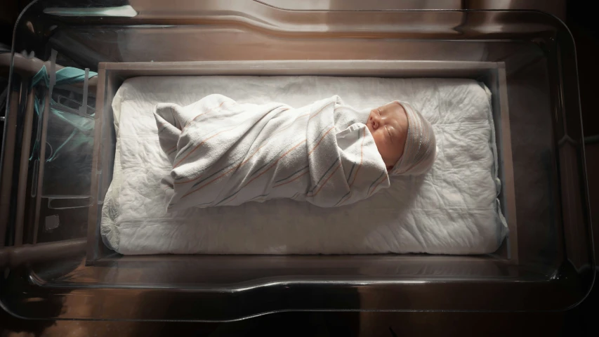 a baby is laying in a cage in the dark