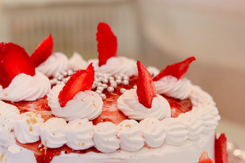 a strawberry cake covered with white frosting and sliced strawberries