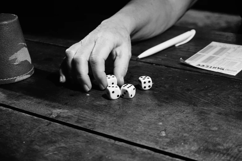 someone's hand touching three dice on the table