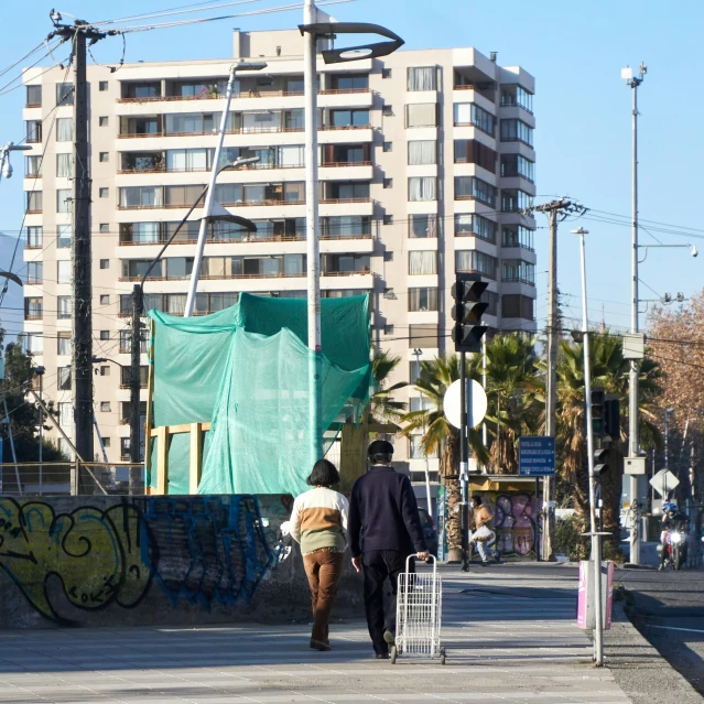 the man and woman walk across a street with the city in the background