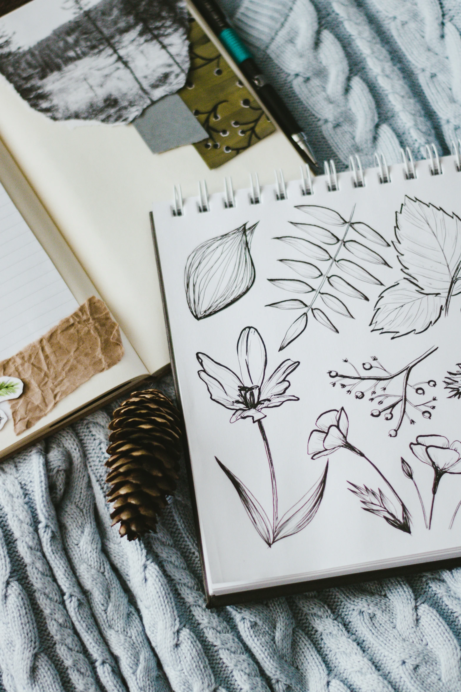 a note book and drawing supplies laid out on a bed