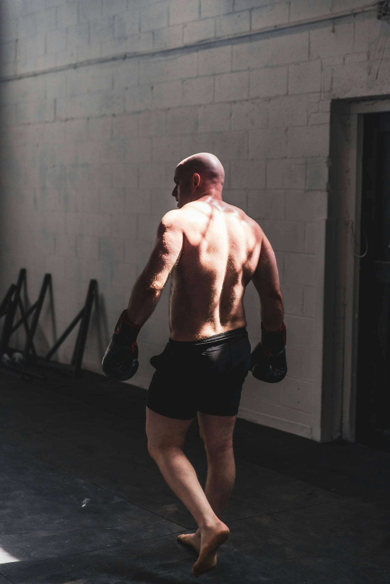 shirtless man wearing boxing gloves walking down the street