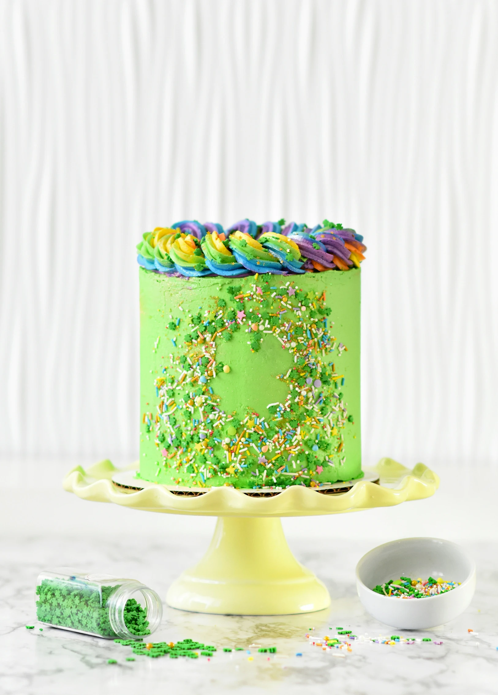 a green cake covered in sprinkles and frosting