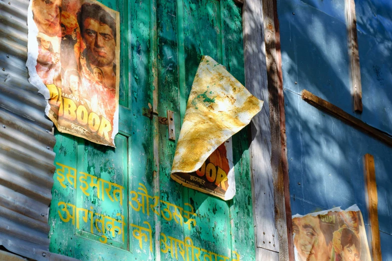 three old posters hang on a green door