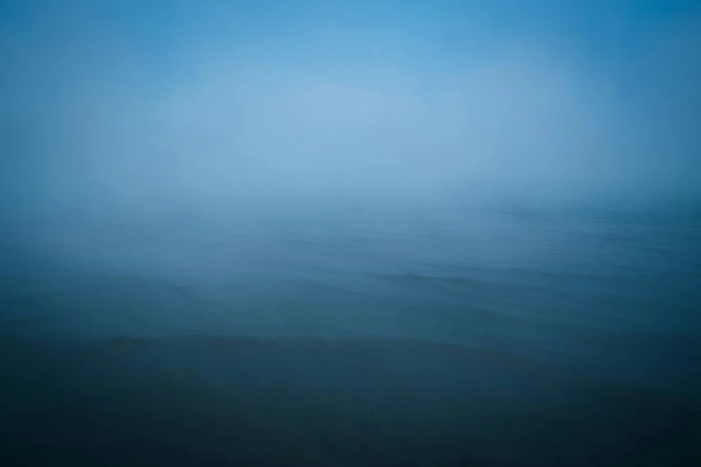 the water is covered with thick fog under a blue sky