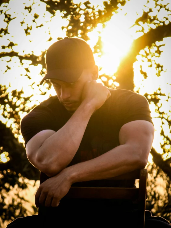 man in black shirt sitting down on a chair and looking away from the camera