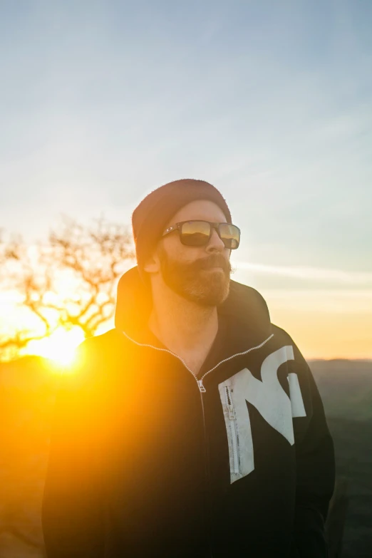 man wearing sunglasses in front of sunset