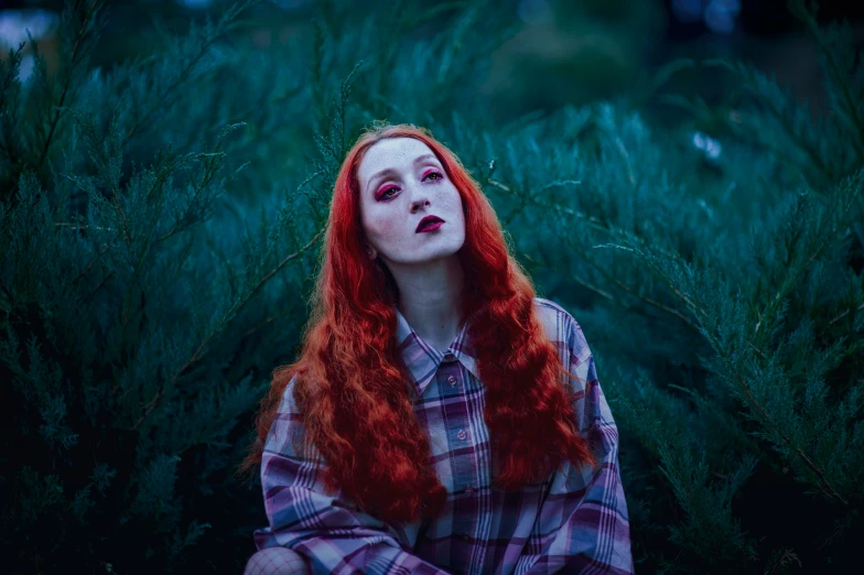 a woman with long red hair sits in tall grass