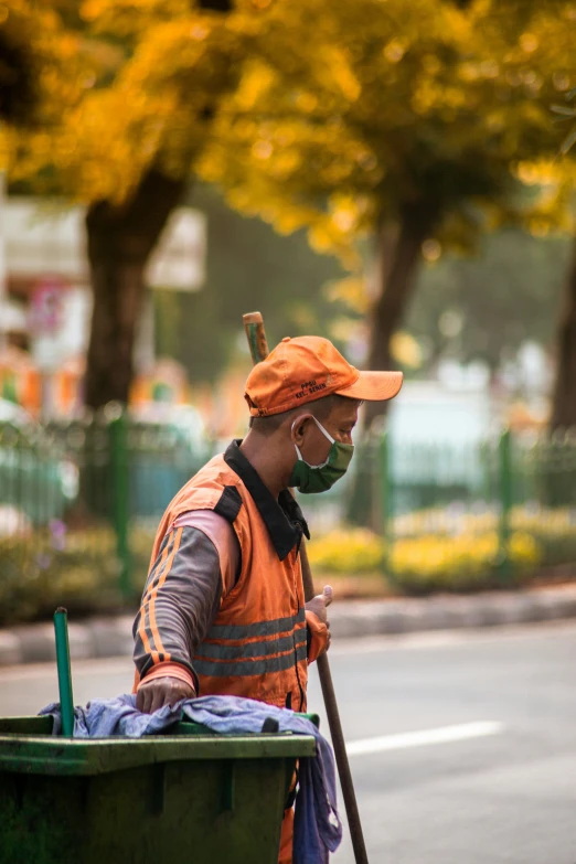 a man in orange jacket and goggles holding a broom