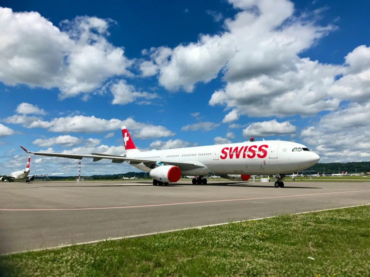 two airplanes on a run way, with clouds in the background