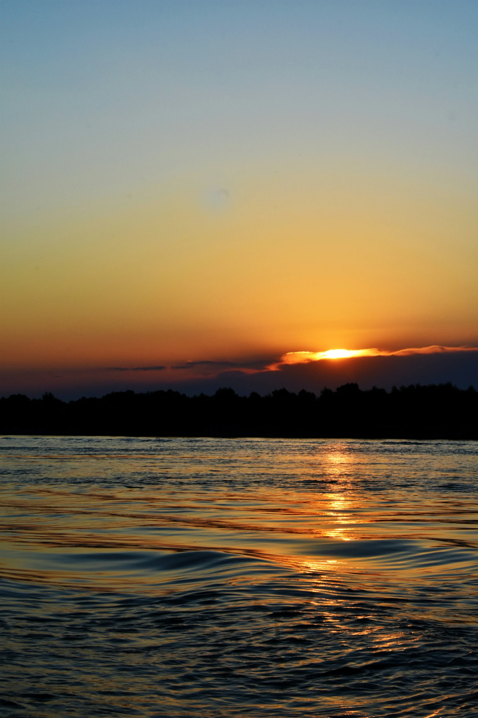 the sun is setting behind the mountains over the water