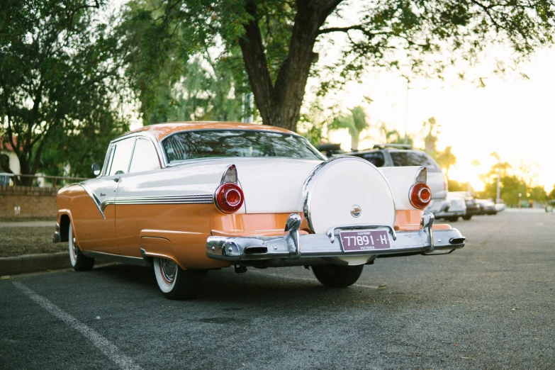 an old car sitting in the parking lot next to trees