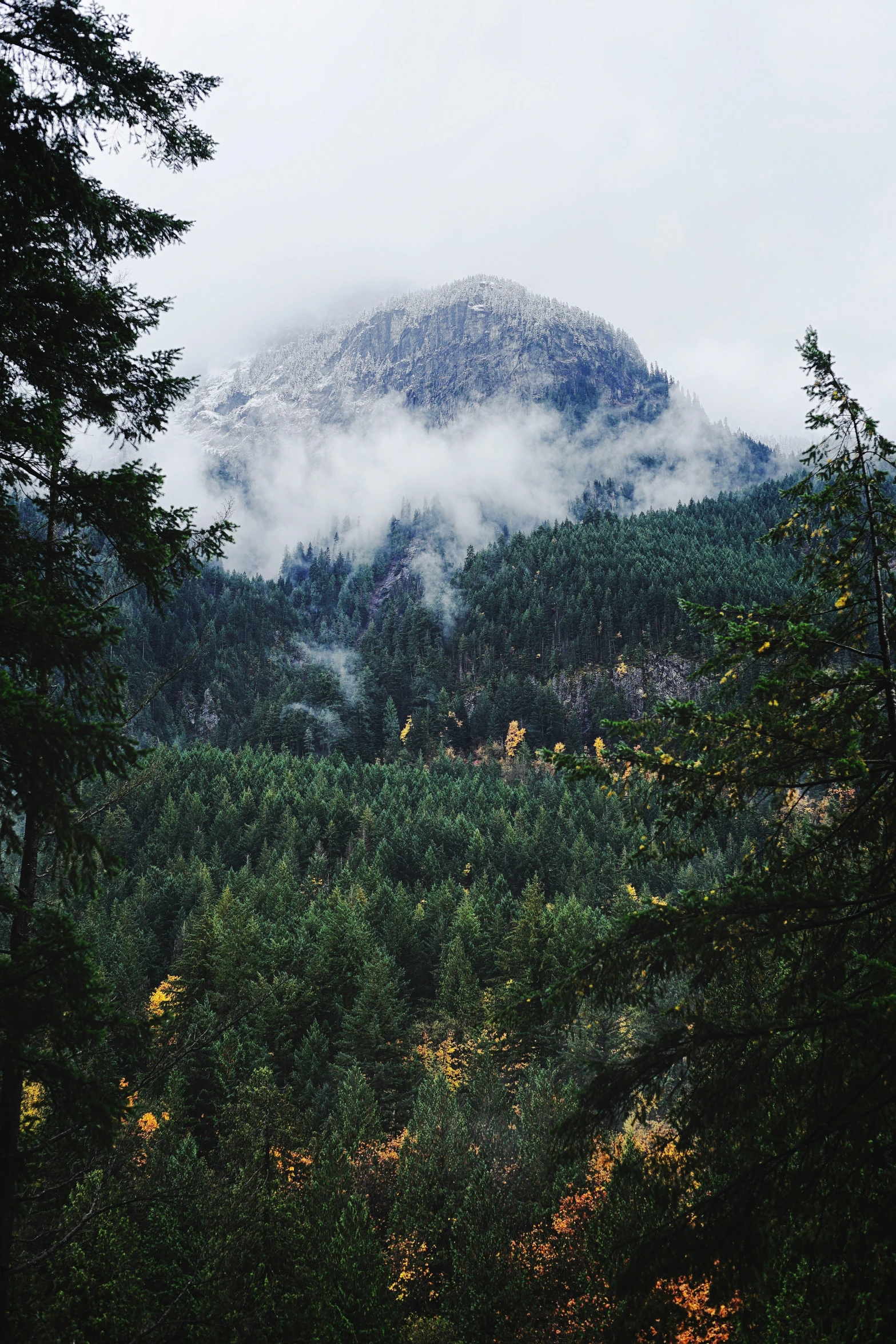 clouds hovering over the hills and trees near by