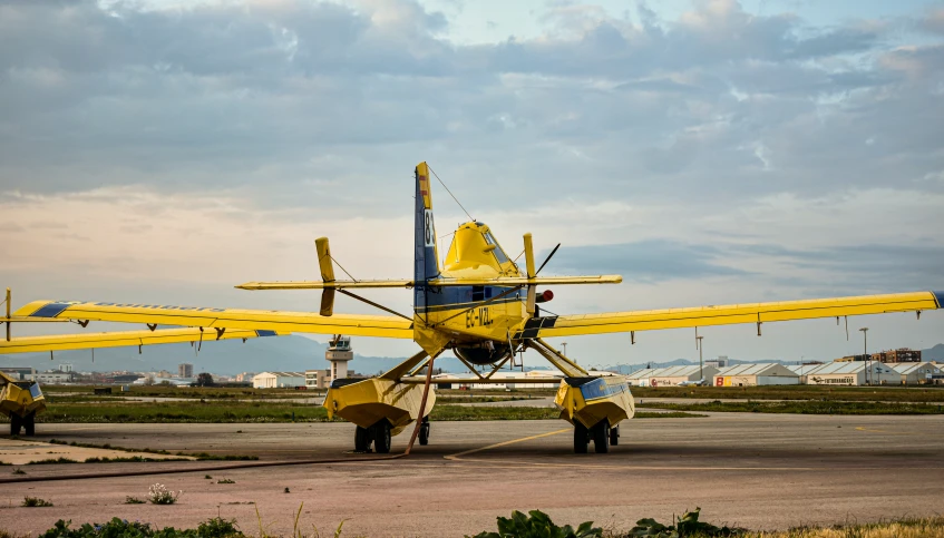 a yellow plane with blue tails on the runway