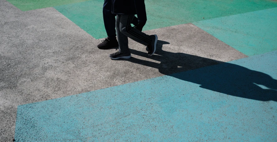 a man with a skateboard walking along a cement walkway