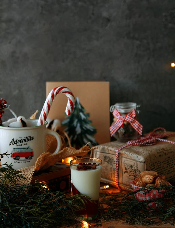 a wooden table with two coffee cups, candy canes and other holiday decorations