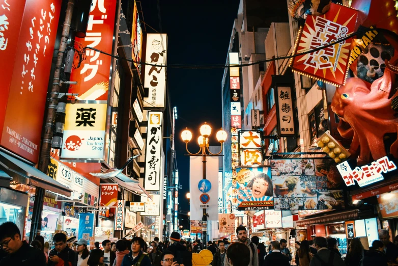 many people are walking through an oriental city at night