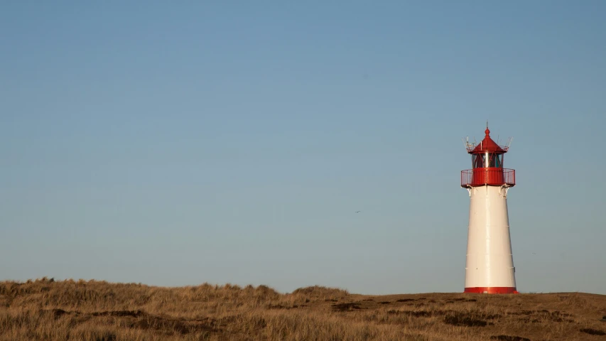 there is a small white and red lighthouse on top of the hill