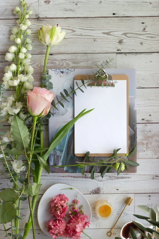 flowers, empty notepad, and vase with honey on table