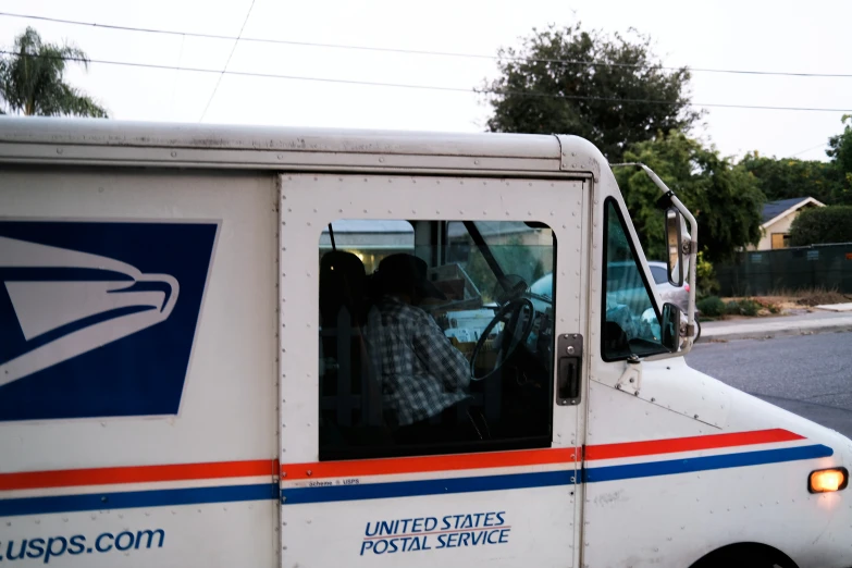 the people are inside of the postal service van