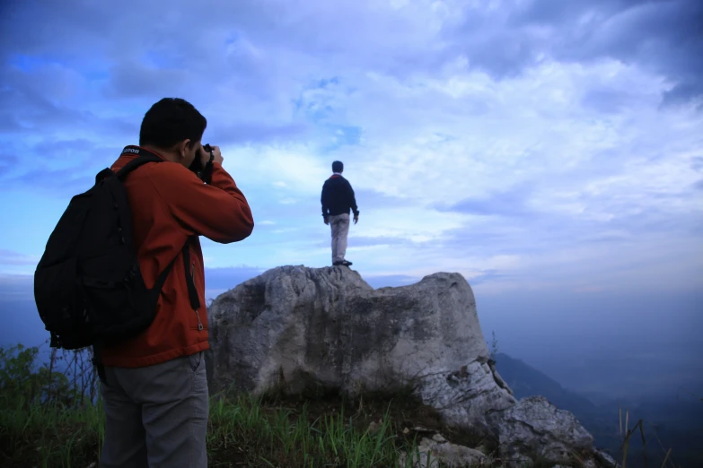 two people on a mountain standing on rocks talking on cellphones