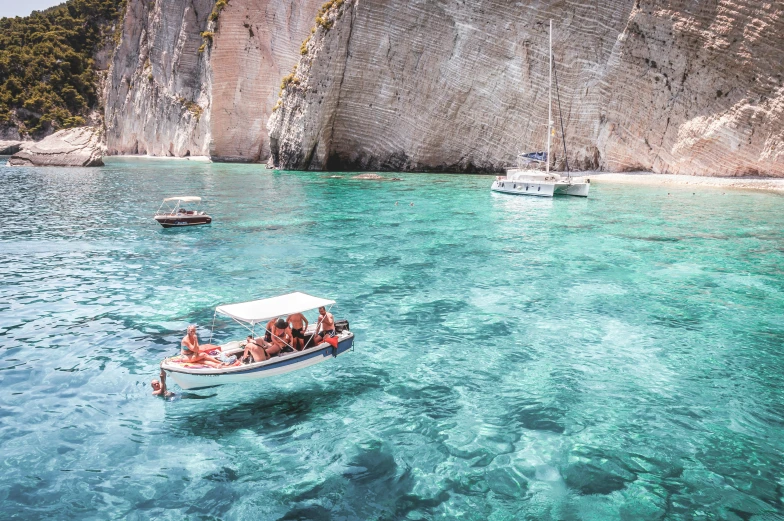 a boat traveling on the water past large rocks