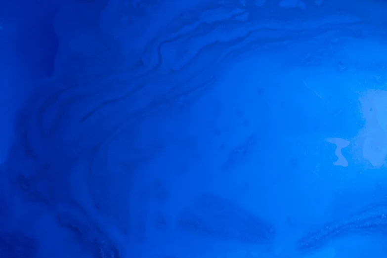 water droplets and streaks are illuminated against the blue color of this liquid