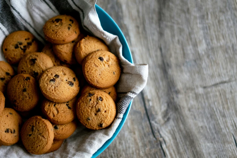 a blue bowl filled with cookies on top of a wooden table