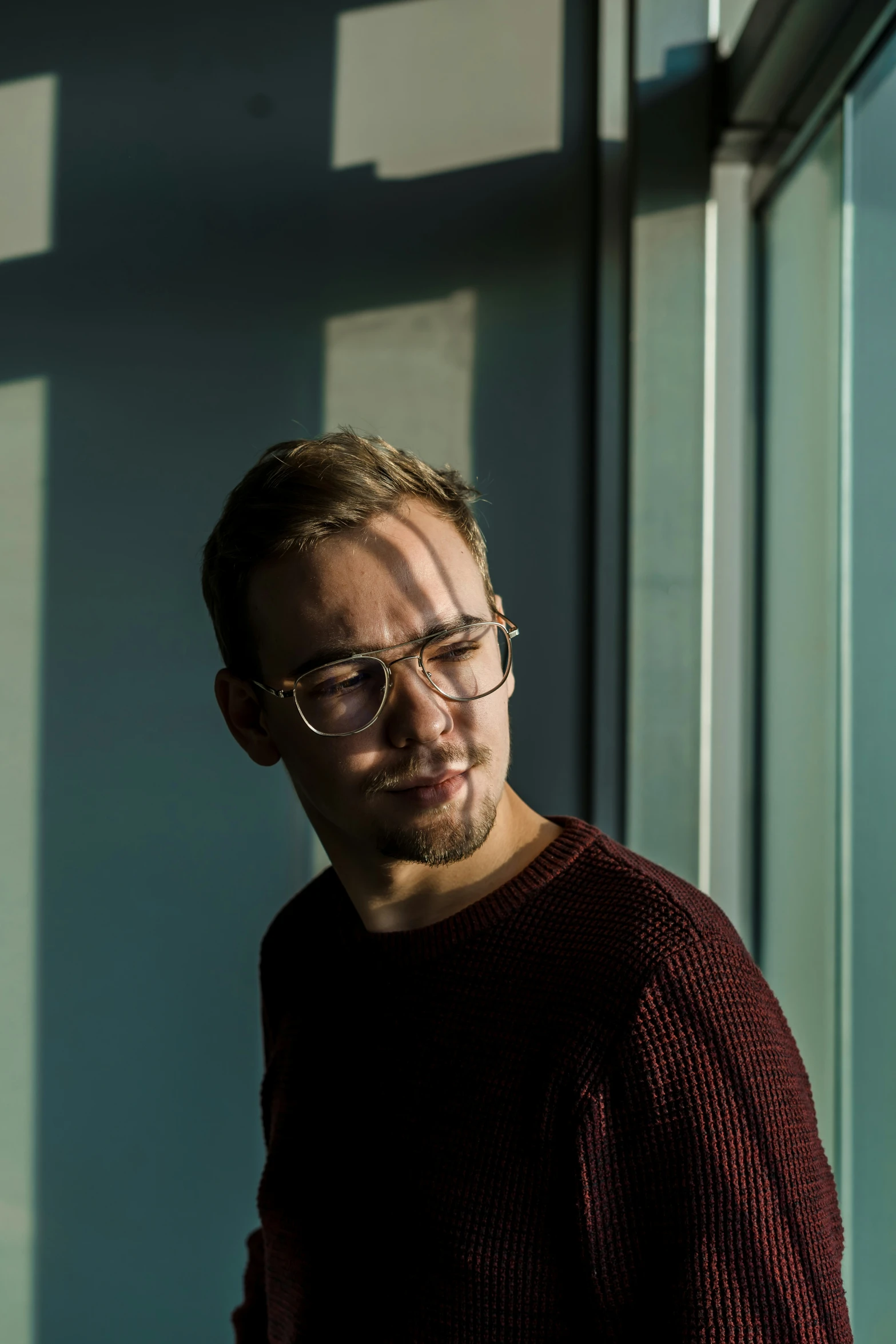 a man with glasses leaning against a wall