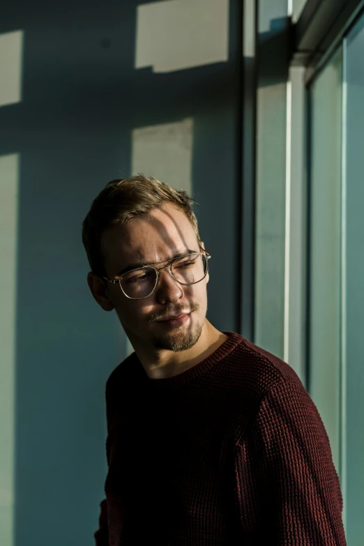 a man with glasses leaning against a wall