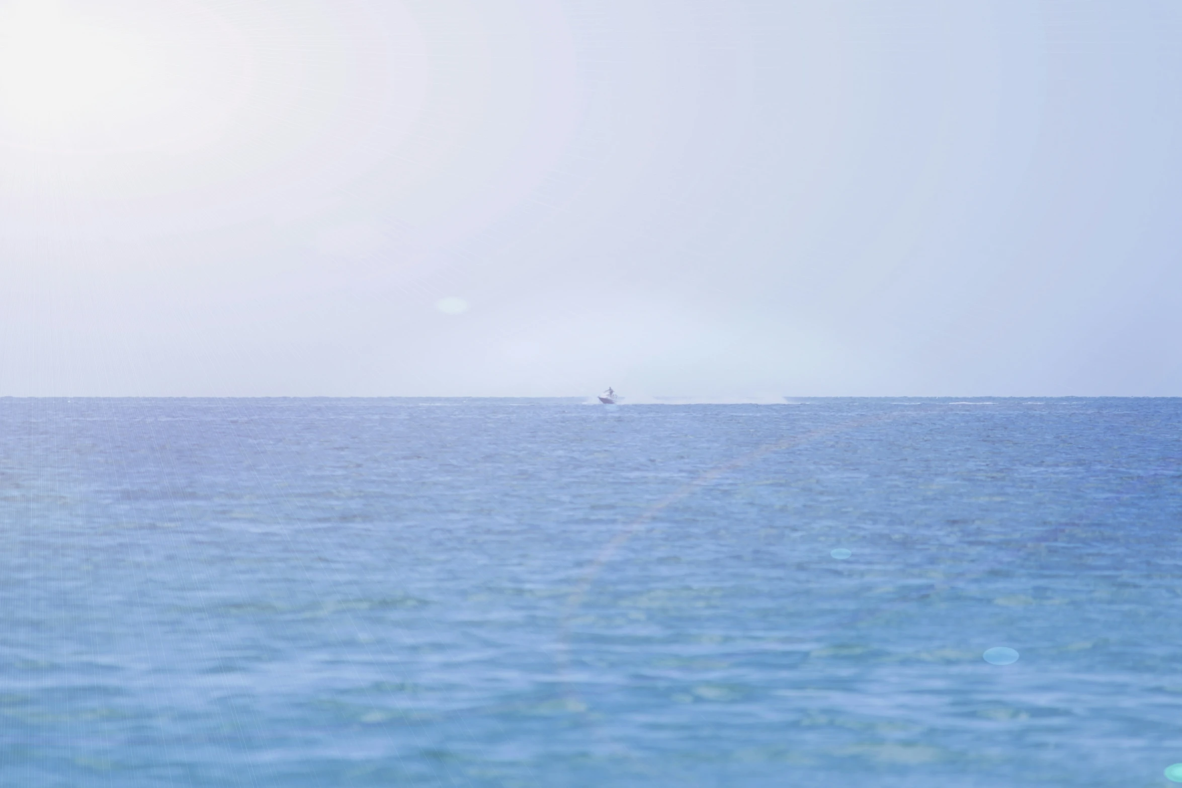 a boat in the distance sailing through calm blue ocean waters