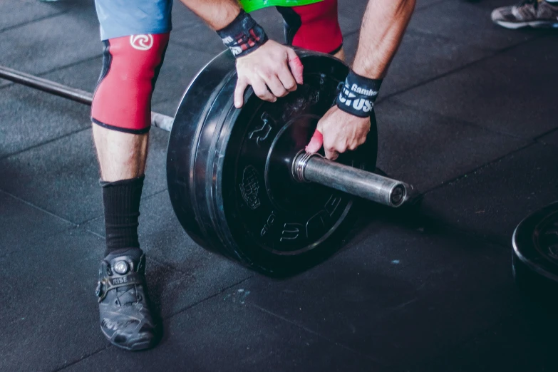 a man holding a barbell on a gym floor