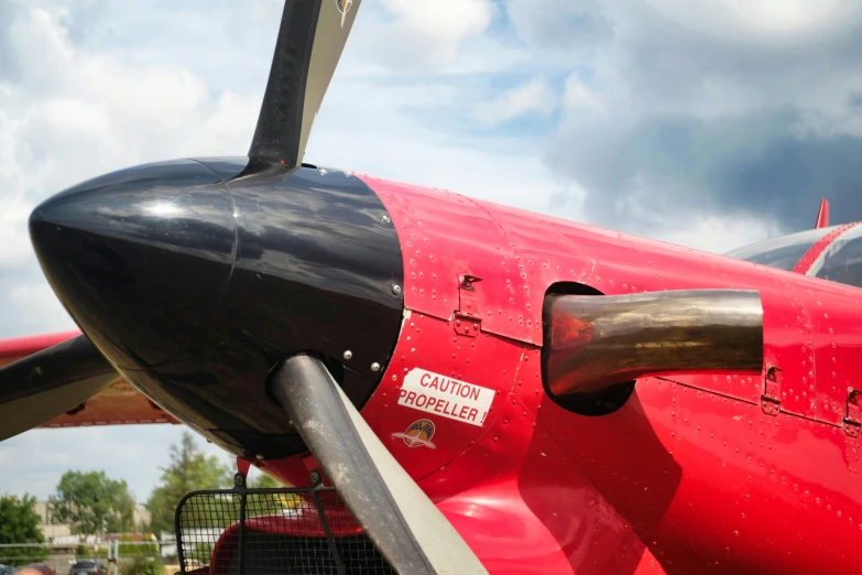 a close - up of the nose of a red airplane with black tips and wings