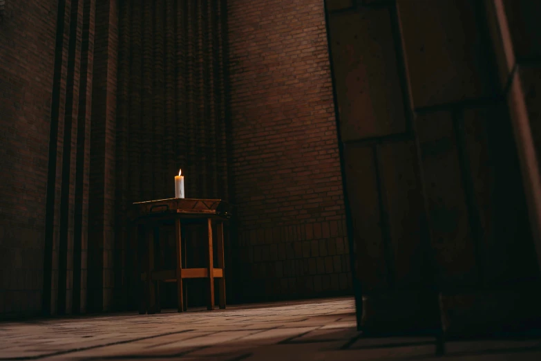 a wooden chair and a lit candle are seen in the dark