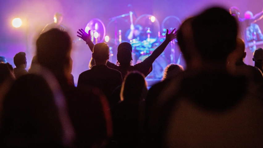 people with their arms up in front of the stage