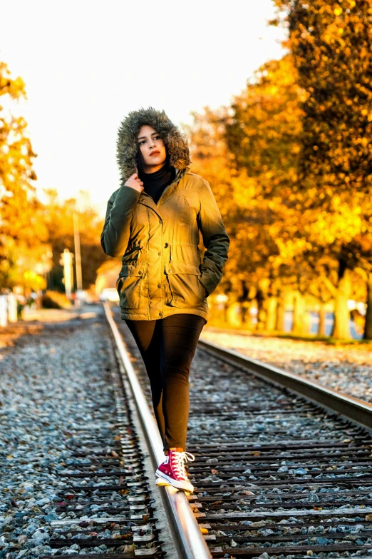 a person walking down the tracks in an autumn jacket