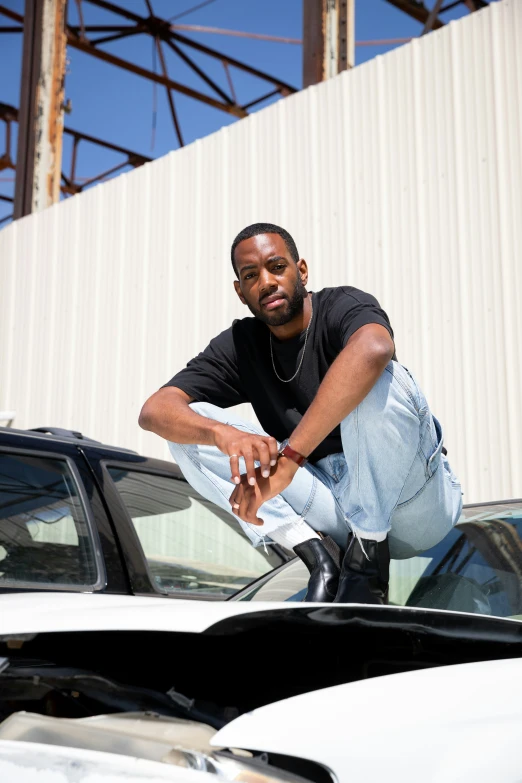 a man squatting next to some cars in front of a building