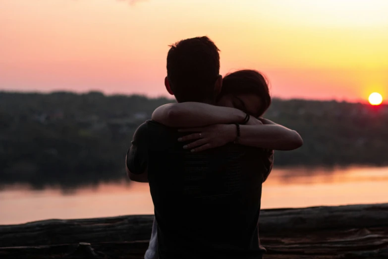 two people that are hugging and looking out over a river